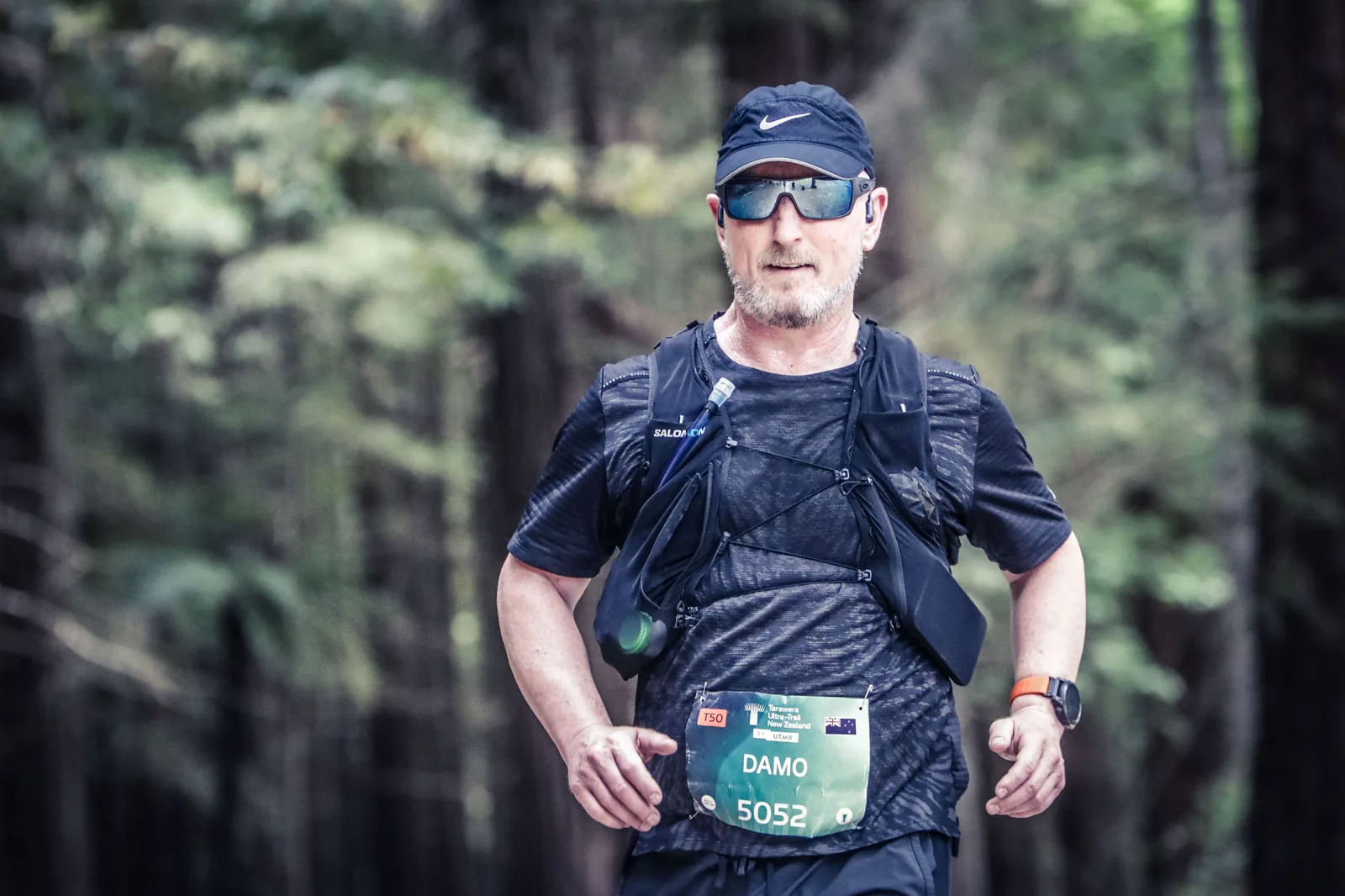 The founder running a forest ultra-trail in a hydration vest and cap.